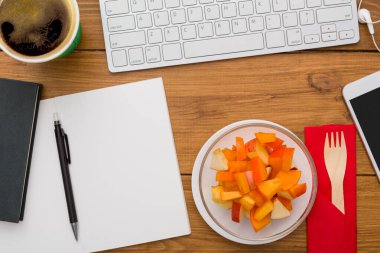 Sağlıklı öğle yemeğinde işyeri. Masaüstü meyve snack folyo konteyner ve ahşap Resepsiyon arka plan üzerinde cep telefonu, en iyi görünüm düz yatıyordu