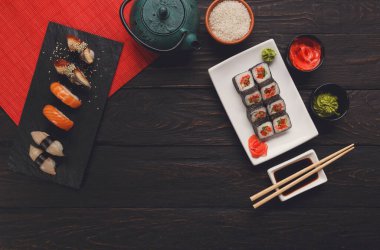Suşi ve rulo arka plan, siyah, en iyi görünümü karede. Renkli Japon restoran yiyecek çay ile ayarla