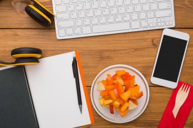 Sağlıklı öğle yemeğinde işyeri. Masaüstü meyve snack folyo konteyner ve ahşap Resepsiyon arka plan üzerinde cep telefonu, en iyi görünüm düz yatıyordu