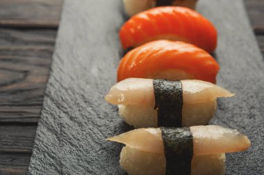 Suşi tabağı. Japon Gıda Restoran, yılan balığı, somon ve balığı suşi closeup koyu arka plan üzerinde. Siyah ahşap üzerine kopya alanı ile POV