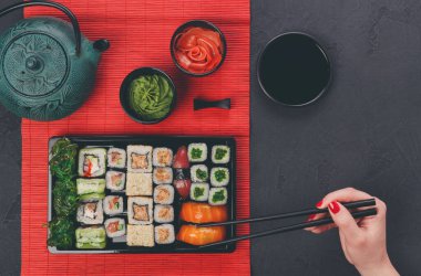 Somon suşi Japon lokantasında yemek, yemek çubukları üstten görünüm ile el. Akşam yemeği, üstten görünüm siyah erkek vardır