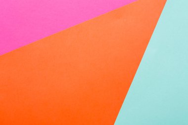 Brightly colored paper shapes in pink, orange, and light blue are layered on a flat surface, creating a vibrant and modern abstract design. This composition showcases creativity and artistic play.