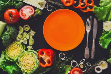 Siyah arka plan üzerine sağlıklı sebze gıda. Taze organik biber, domates, lahana ve diğer yemekler kopya alanı boş portakal plakalı