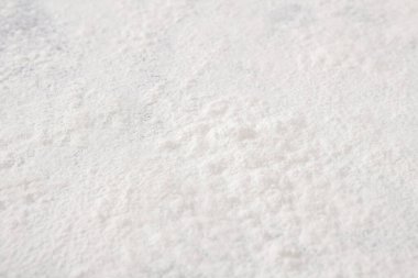 Parlak bir mutfakta, ahşap bir tezgahın üzerine eşit bir beyaz toz tabakası yayılır. Doğal ışık sahneyi aydınlatıyor. Bu da pişirme ya da pişirme sürecini gösteriyor..