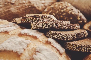 Taze pişmiş ekmek ve susamlı kurabiyeler, çeşitli doku ve renklerin sergilendiği, ahşap bir yüzeyde dinleniyor. Sıcak aroma ve hoş bir sunum hoşgörüyü davet ediyor..