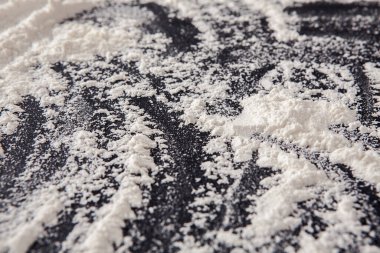 Un karanlık bir yüzeye yayılarak çeşitli desenler ve dokular oluşturur. İnce parçacıklar, beyaz ve siyah arasındaki zıtlığı gösteren sanatsal bir görüntü yaratıyor..