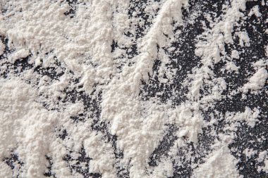 Bir kat un mutfakta koyu bir yüzeyi kaplar. Un dağılmış ve karışım belirtileri gösteriyor. Cihazlar ve diğer pişirme malzemeleri çevrede kullanılabilir.