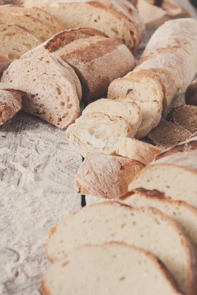 Ekmek arka plan. Beyaz ve çavdar, ahşap masa üzerinde tüm ve dilimlenmiş somun closeup un serpilir. Tarifi için alay, uzay, dikey Kopyala