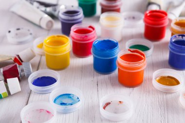 Sanatçı işyeri. Beyaz ahşap masa arkaplanındaki renk gouache kavanozları ve akrilik boyalar, boşluğu kopyala