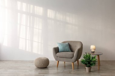 Yastıklı rahat bir koltuk, masada parlak bir lamba, saksıda bitki ve oturma odasında gri duvarda bir kanepe. Eski mobilyaları olan çağdaş tasarım, İskandinav tarzı, hiç kimse