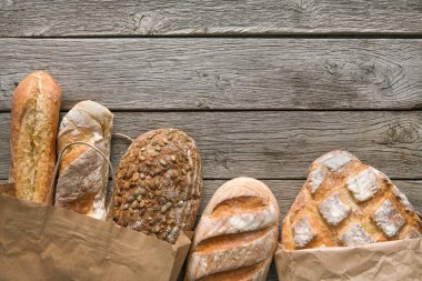 Ekmek sınırında rustik ahşap kopya alan arka plan ile. Kağıt torbalarda kahverengi ve beyaz somun