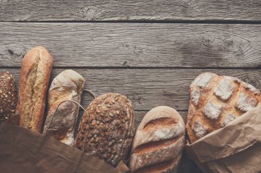 Ekmek sınırında rustik ahşap kopya alan arka plan ile. Kahverengi ve beyaz tam tahıl somun natürmort kompozisyon buğday unu ile çevresinde serpilir.