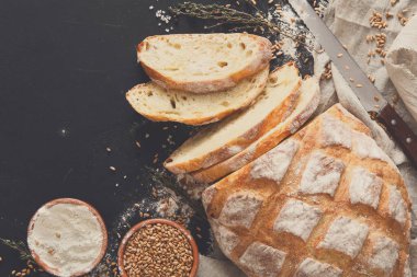 Fırın arka planı, siyah üzerine büyük ekmek. Kopya alanı olan un ve tahıl