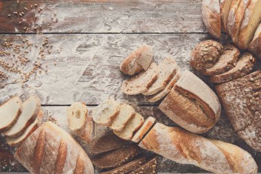 Ekmek çerçeve rustik ahşap arka plan üzerine dilimlenmiş, uzay kopyalayın. Kahverengi ve beyaz somun ve un üst çevresinde serpilir buğday unu ile kompozisyon görüntüleme.