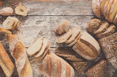 Ekmek çerçeve rustik ahşap arka plan üzerine dilimlenmiş, uzay kopyalayın. Kahverengi ve beyaz somun ve un üst çevresinde serpilir buğday unu ile kompozisyon görüntüleme.