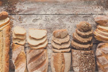 Ekmek çerçeve rustik ahşap arka plan üzerine dilimlenmiş, uzay kopyalayın. Kahverengi ve beyaz somun ve un üst çevresinde serpilir buğday unu ile kompozisyon görüntüleme.