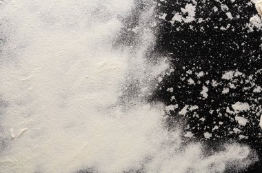 Koyu renkli bir yüzey beyaz unla kaplıdır ve çarpıcı bir kontrastla dokunun yapısını ortaya çıkarır. Bu kurulum pişirme, pişirme veya mutfak sunumları için idealdir..