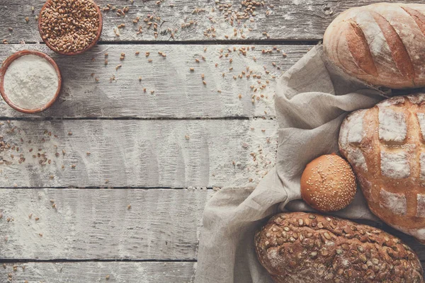 Ekmek çerçeve rustik ahşap arka plan, kopya alanı üzerinde. Kahverengi ve beyaz somun ve buğday unu ile un natürmort kompozisyon çevresinde serpilir.