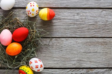 El yapımı DIY boyalı yumurta saman içinde ahşap arka plan üzerinde iç içe. Rustik masa üstten görünüm üzerinde renkli tatil dekorasyon