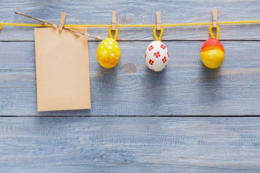 Renkli paskalya yumurtaları bir ipte askıya alınır ve çeşitli şekillerde sergilenir. Yumurtaların yanında boş bir not kırsal bir ahşap zemine yapıştırılır. Kutlama notları için birebirdir..