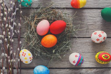 Parlak renkli Paskalya yumurtaları samanla dolu bir yuvanın etrafına sergilenir. Canlı renkler ve desenler ilkbahar geleneklerini ve mevsimsel keyfi kutluyor..