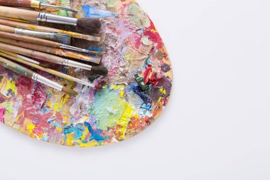 Sanatçılar paletle renkli boya konturları ve beyaz izole arka plan, üstten görünüm, düz lay, nesne üzerinde Boya fırçaları