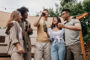 Kamp gezisinde bira içen, sohbet eden, şakalaşan ve dışarıda birlikte gülen çok ırklı genç insanlar. Bin yıllık çeşitli arkadaşlar yaz tatilinde karavanın yanında alkolle parti yapıyorlar.