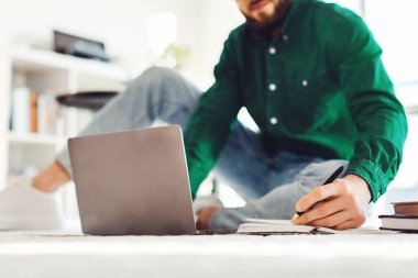 Bilgisayarlı iş raporlarını kullanarak not alan ya da içeride oturarak gözlük takarak internetten öğrenen bir adamın görüntüsü. E-Öğrenme Konsepti. Seçici Odaklanma Elle Tutma Kalemi