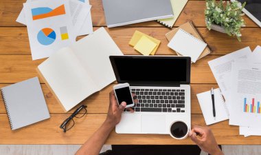 Office çalışma alanı üstten görünüm. Afrikalı-Amerikalı işadamı ahşap masa başında çalışan dizüstü bilgisayar ve çeşitli nesneleri her yerde kullanma