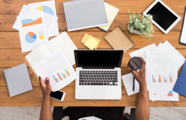 Office çalışma alanı üstten görünüm. Afrikalı-Amerikalı işadamı ahşap masa başında çalışan dizüstü bilgisayar ve çeşitli nesneleri her yerde kullanma