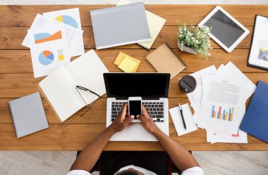 Office çalışma alanı üstten görünüm. Afrikalı-Amerikalı işadamı ahşap masa başında çalışan dizüstü bilgisayar ve hareket eden kullanma