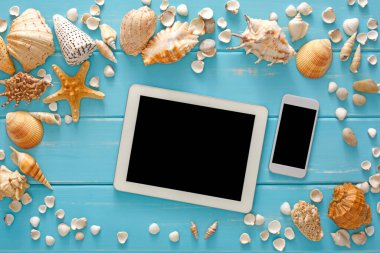 Dijital tablet ve akıllı telefondan bilet rezervasyonu, boş ekran, deniz tatili geçmişi, mavi ahşap deniz kabukları, maket