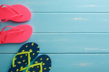Mavi ahşap üzerinde parmak arası terlikler, fotokopi alanı olan üst manzara. Plaj aksesuarları, tatil geçmişi