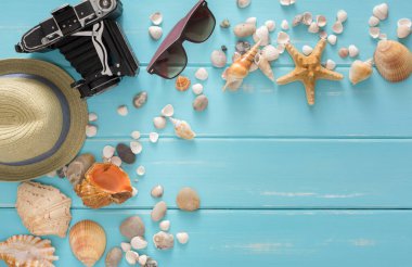 Tatil antika arka plan mavi ahşap, en iyi kopya alanı görünümle. Plaj aksesuarları, retro fotoğraf makinesi, güneş gözlüğü ve kabukları
