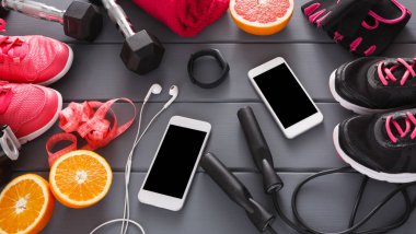 Parlak renkli spor ayakkabıları ve ekipmanlar spor salonunda düzenlenir. Portakal ve greyfurt gibi sağlıklı atıştırmalıklar telefon ve spor aletlerinin yanında oturur..