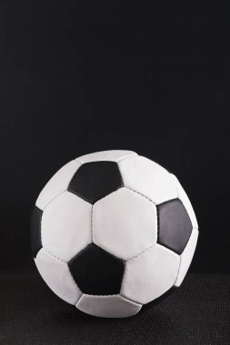 Bir futbol topu siyah arka planı olan karanlık bir yüzeye oturur. Topun klasik beyaz ve siyah altıgen deseni var. Yuvarlak ve oyun ya da antrenman için hazır..