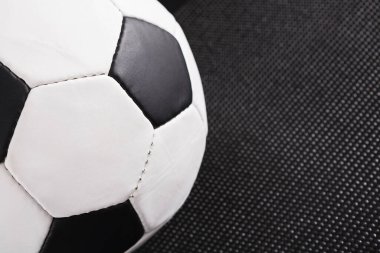 Bir futbol topu koyu dokulu bir yüzey üzerinde dinleniyor. Topun siyah ve beyaz yamalı klasik bir tasarımı var. Bu ayar futbol oyuncuları için tipik bir antrenman ya da alıştırmadır..