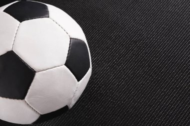 Siyah beyaz panelleri olan bir futbol topu karanlık bir yüzeye oturur. Top, oyun için bekler gibi konumlandırıldı. Ortam muhtemelen bir antrenman alanı ya da spor tesisi..