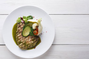 Bir tabakta iyi baharatlı ızgara balık ve salatalık dilimleri, kiraz domatesleri ve karışık yeşilliklerle süslenir. Karnabahar balığın yanında oturur, düzenli bir şekilde sunulur..