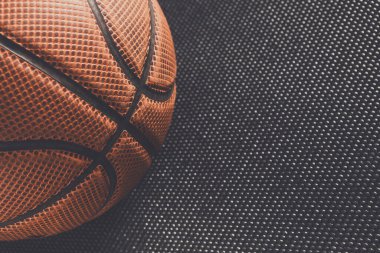 Bir basketbol topu desenli siyah bir yüzeye yerleştirilir. Top, bir oyun veya alıştırma oturumuna hazır olduğunu belirten belirgin dizayn ve dikişlerini gösterir.