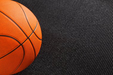 Bir basketbol topu siyah desenli bir yüzeye dayanır. Turuncu top tipik tasarım detaylarını gösteriyor. Ayar koyu arkaplana karşı topların rengini vurgular.