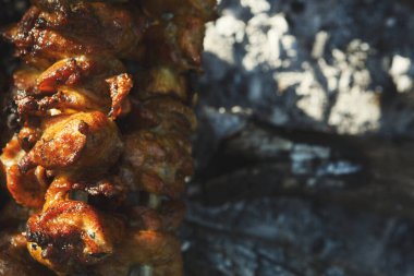 Et parçaları parlayan kömürün üzerinde ızgara yapıyor. Yemekler güzel bir kahverengiyi gösteriyor ve açık havada pişiriliyor. Ateşten yükselen duman yavaşça pişiyor..