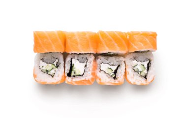 Beyaz bir yüzeyde bir suşi rulosu düzgünce sunuluyor. Düzenleme, suşi rulolarının üzerine salatalık ve pirinç dolu somon parçalarını içeriyor. Bu Japon mutfağını gösteriyor..