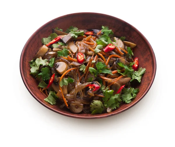 Kahverengi bir kasede sebze, ot ve erişte karışımı bulunur. Kırmızı biber dilimleri renk katar. Çanak beyaz arka plana yerleştirilir. Kişniş gibi taze bitkiler malzemeler arasında görülebilir..