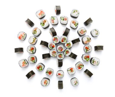 Çeşitli suşi ruloları dairesel bir düzene yerleştiriliyor. Her rulo balık ve sebze de dahil olmak üzere farklı dolgulara sahiptir. Arka plan bembeyaz, suşiyi öne çıkarıyor..