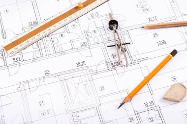 Bina planlarına cetvel, pusula, kalem ve silgi de dahil olmak üzere mimari aletlerin bir koleksiyonu. Çalışma alanı bir inşaat projesi için yaratıcılık ve planlama belirtileri gösteriyor..