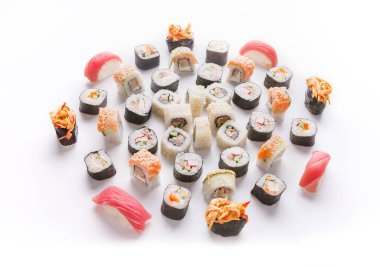 Çeşitli suşi türleri beyaz bir yüzey üzerinde dairesel bir şablon içinde serilmiştir. Bu ekran çeşitli dolgu maddeleri ve malzemelerle birlikte ruloları içerir. Çeşitli renkler ve şekiller görünür..