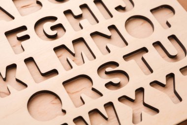 Görüntü, A 'dan Z' ye büyük harflerle yazılmış tahta bir tahtayı gösteriyor. Harfler açıkça görülüyor ve el yapımı veya eğitim amaçlı kullanılabiliyor. Tahtanın hafif bir ahşap kaplaması var..