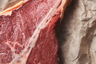 Yakından bakıldığında, mutfak bölgesindeki bir parça kahverengi kağıda sığır etinin büyük ham kesikleri görülüyor. Bu et kesikleri pişirilmeye ya da hazırlanmaya hazır..