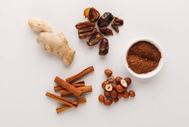 Zencefil kökü, hurma ve fındık düz bir yüzeye yerleştirilir. Tarçın çubukları ve bir kase yer baharatı da dahil. Bu düzenleme yemek ve pişirmede kullanılan bazı malzemeleri gösterir.